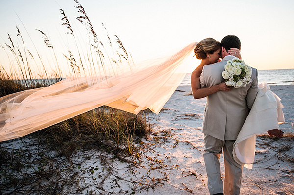 groom-carrying-his-bride-onto-the-sandy-beach-bridal-style-carry-romantic-beach-wedding-Paul-Johnson-Photography